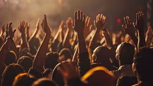 Crowd of people at a concert with hands raised in the air during a performance